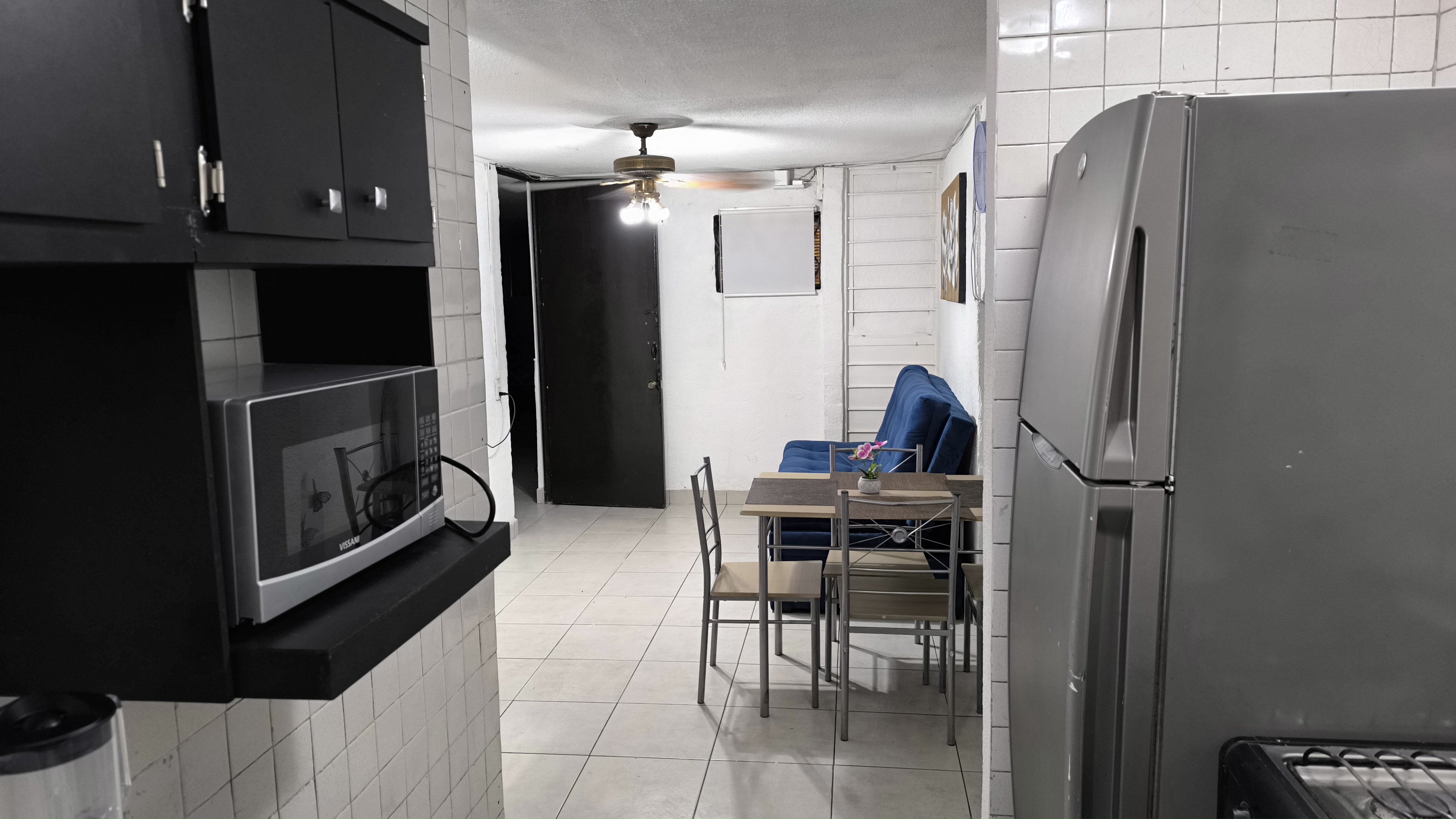 El Loft donde se ve la cocina, el refrigerador, el comedor y el sillón